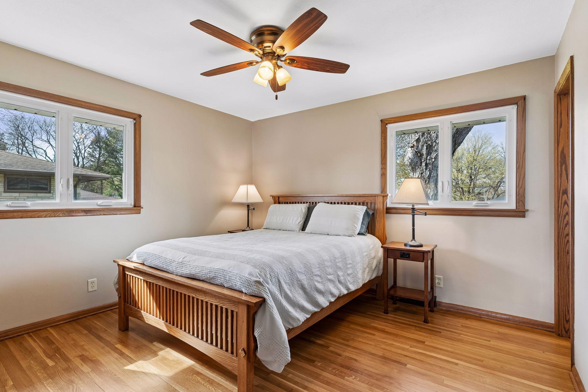 12x12 Main floor Bedroom #1 with freshly refinished oak hardwood floors, new paint, hardwood trim, updated west and north-facing windows, and attached Half Bathroom.