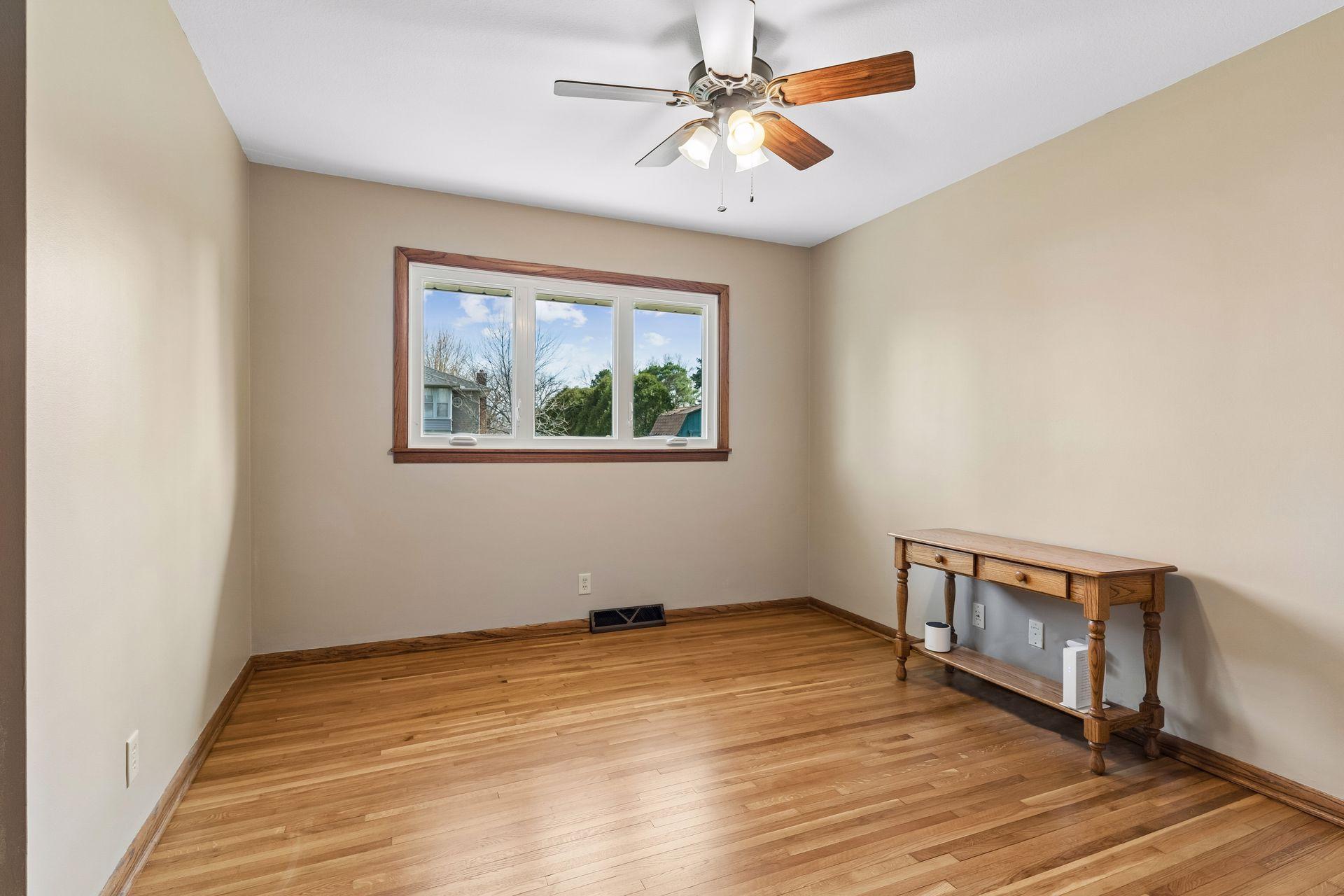12x11 Main floor Bedroom #3 with freshly refinished oak hardwood floors, new paint, hardwood trim, updated south-facing windows.