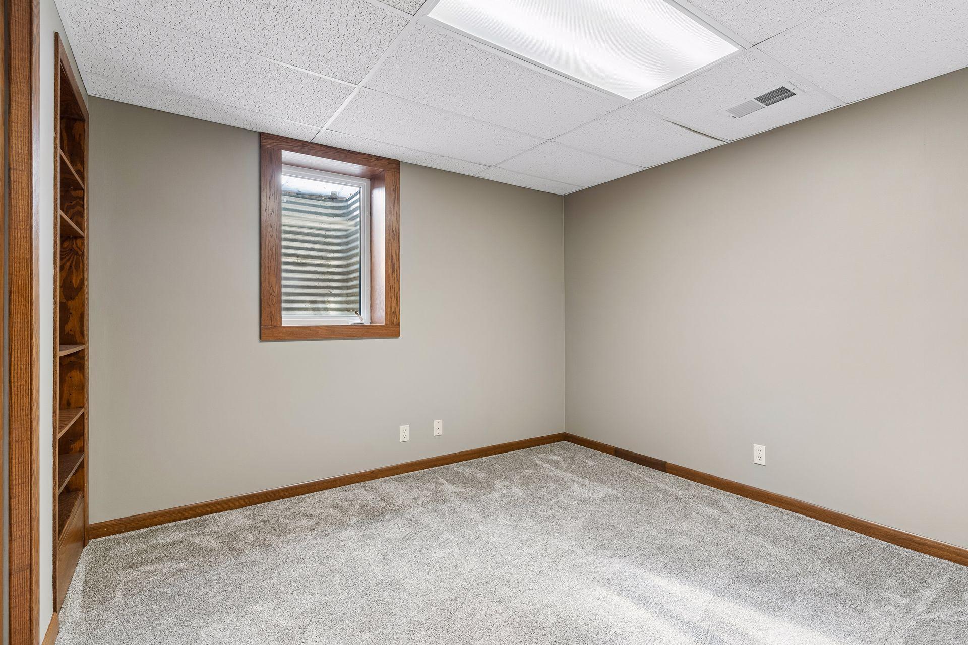 12x10 Lower Level bedroom #5 Freshly Painted Walls, wood trim, and west-facing egress window.