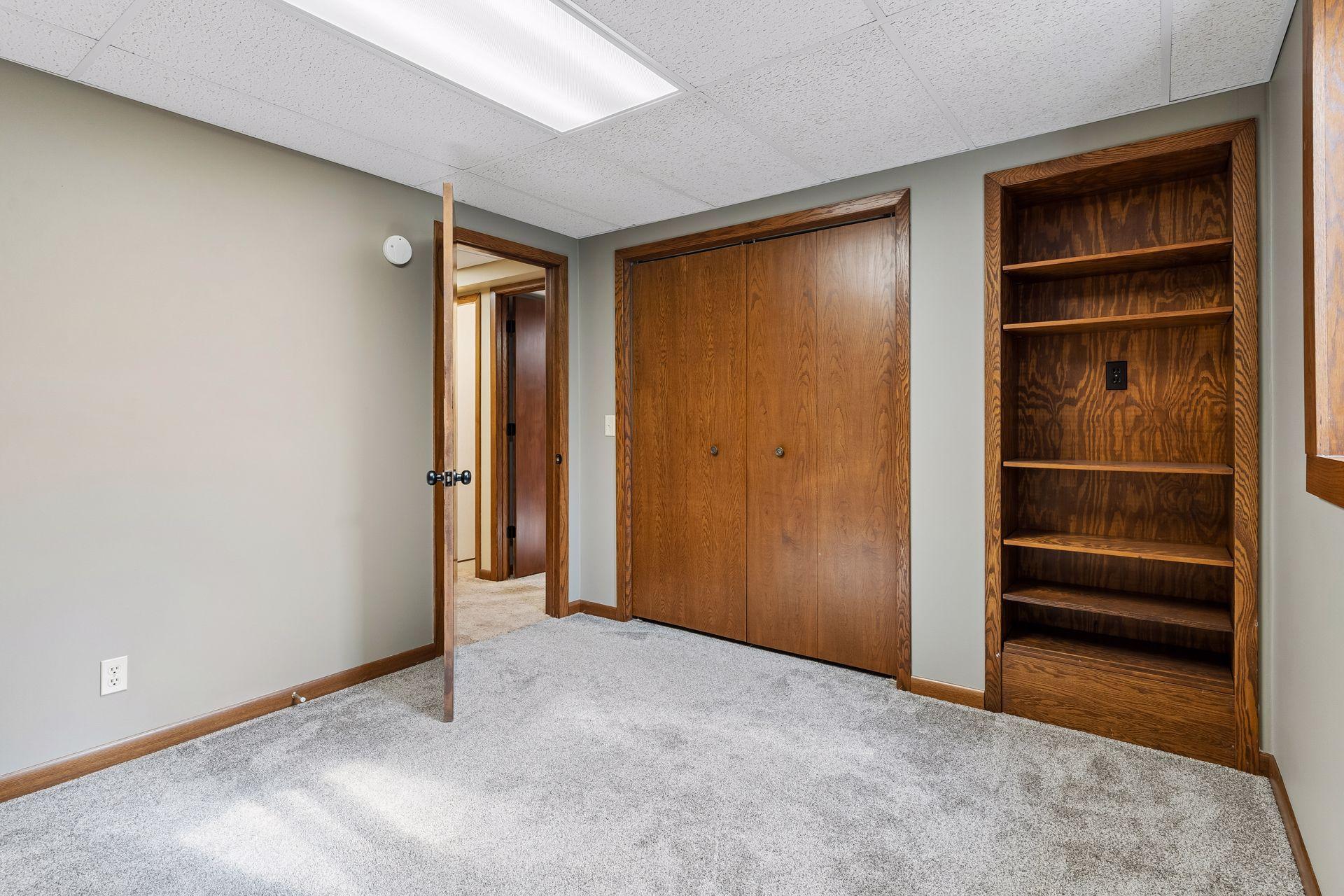 12x10 Lower Level bedroom #5 Freshly Painted Walls, wood trim, and west-facing egress window.