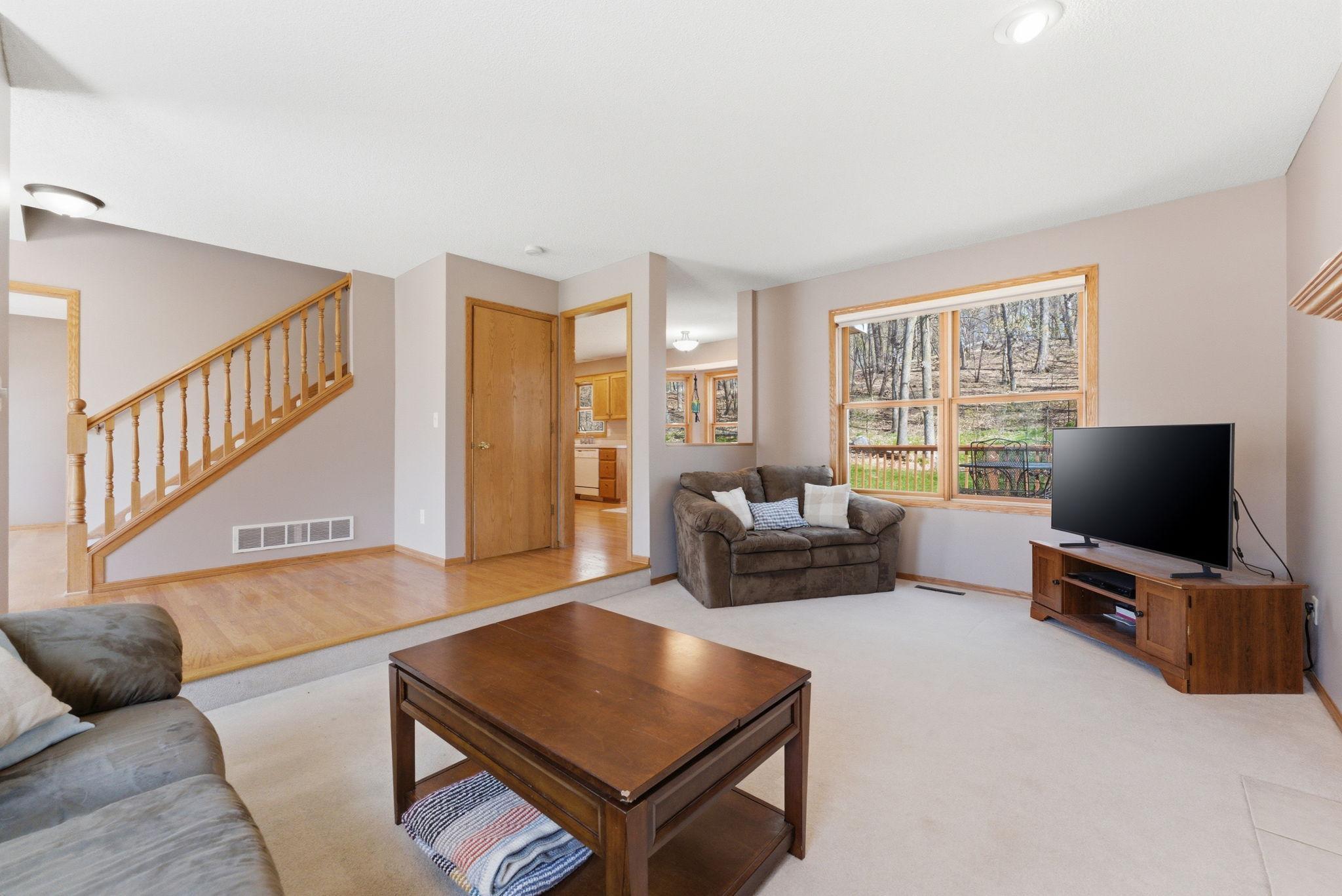 Another view of the main level living room shows the view to the backyard and the floorplan flows into the dining room and kitchen area.