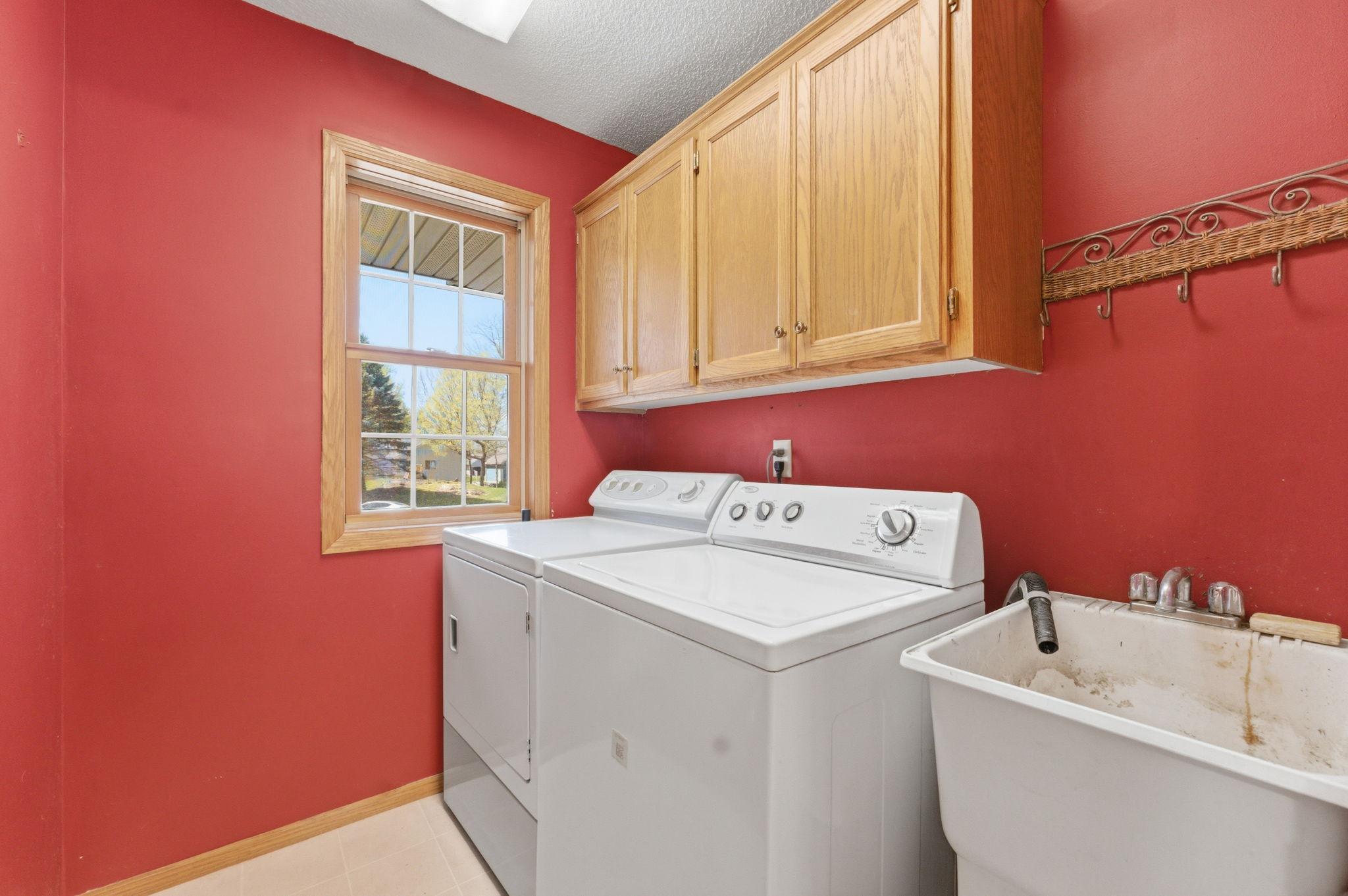 Main level laundry with utility sink and upper cabinets.