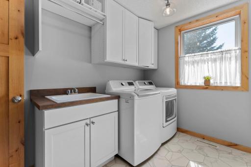 Completing the main level is a well-appointed laundry room featuring tile flooring (2024), built-in cabinetry, a storage closet, a utility sink, and new washer and dryer units installed in 2023.
