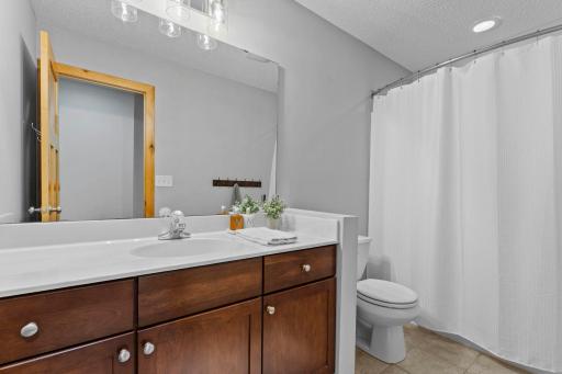These bedrooms are conveniently located near a shared full bathroom featuring tile flooring, a single-sink vanity, and a tub/shower combination.