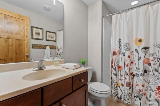 Just down the hall is a three-quarter bathroom featuring tile flooring, a single-sink vanity, and a walk-in shower.