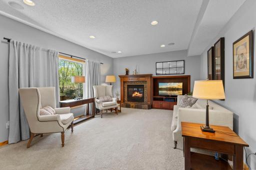 The spacious main-level family room is designed for both comfort and functionality, offering soft carpeting, a built-in entertainment center, and a cozy gas fireplace that serves as the focal point of the space.