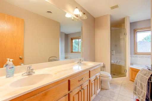 Well-appointed ensuite features a dual-sink vanity, walk-in tiled shower, and relaxing tub.