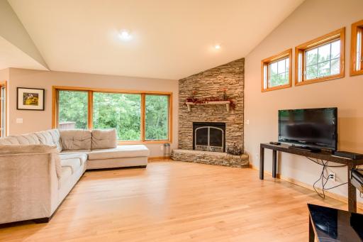 Spacious living area featuring soaring ceilings, abundant natural light, and a striking floor-to-ceiling stone fireplace.