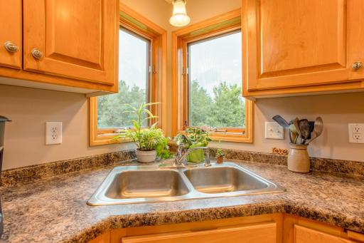 Corner windows above the sink bring in natural light and offer relaxing views of the surrounding greenery.