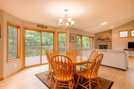 Sun-filled dining area with large windows and direct deck access overlooking the private, tree-lined backyard.