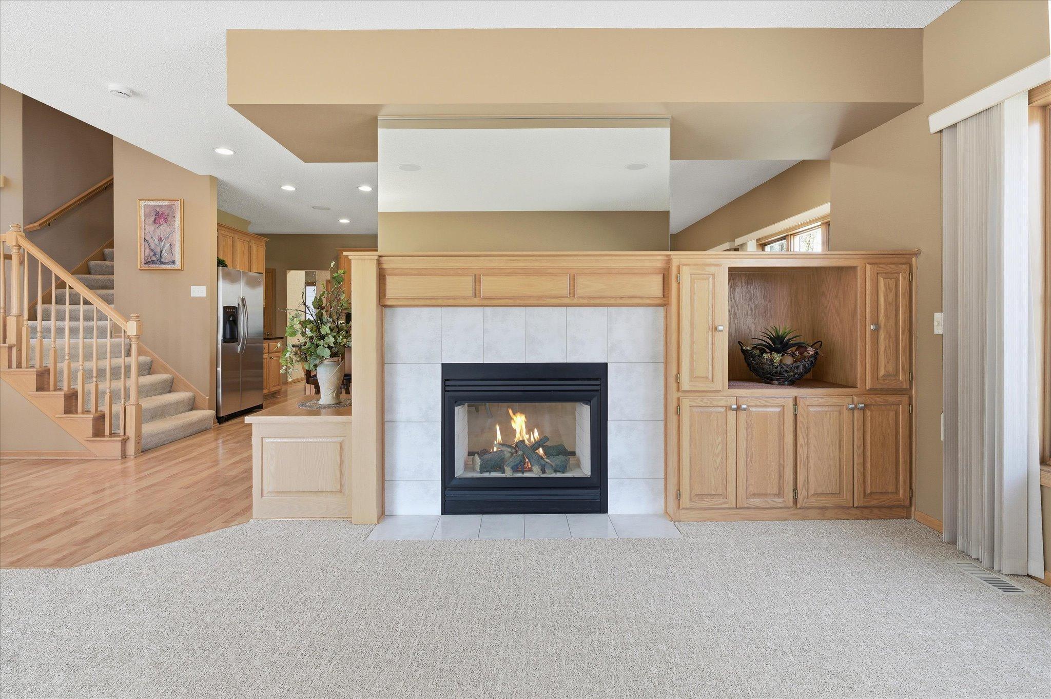 Open Family Room features: see-thru gas fireplace w/tile surround, `open peninsula, floor to ceiling windows, new carpeting (2025). Great open flexible space for entertaining/relaxing