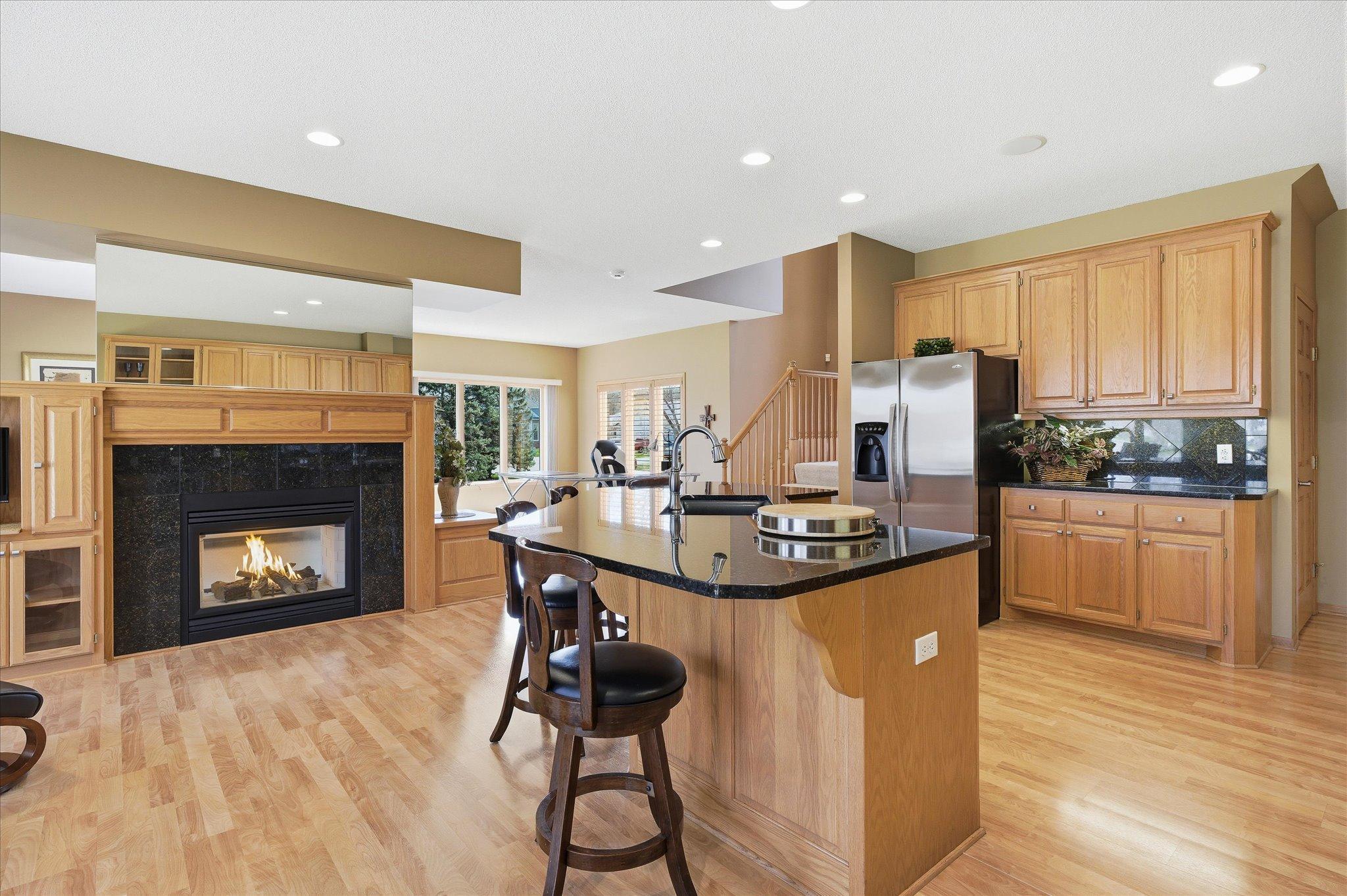 Cozy gas fireplace with granite surround opens to both Kitchen and Family Room