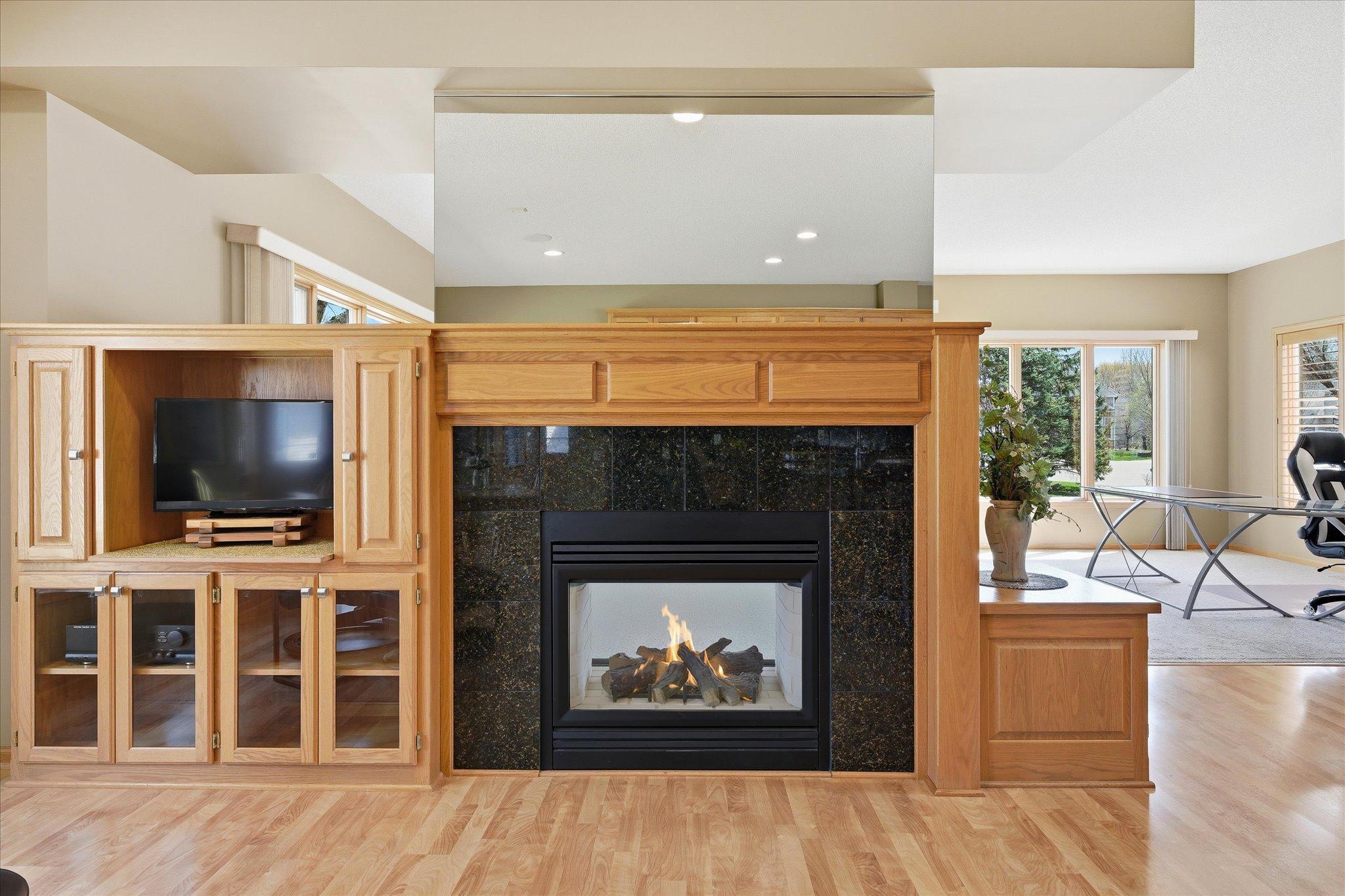 Cozy gas fireplace with granite surround opens to both Kitchen and Family Room