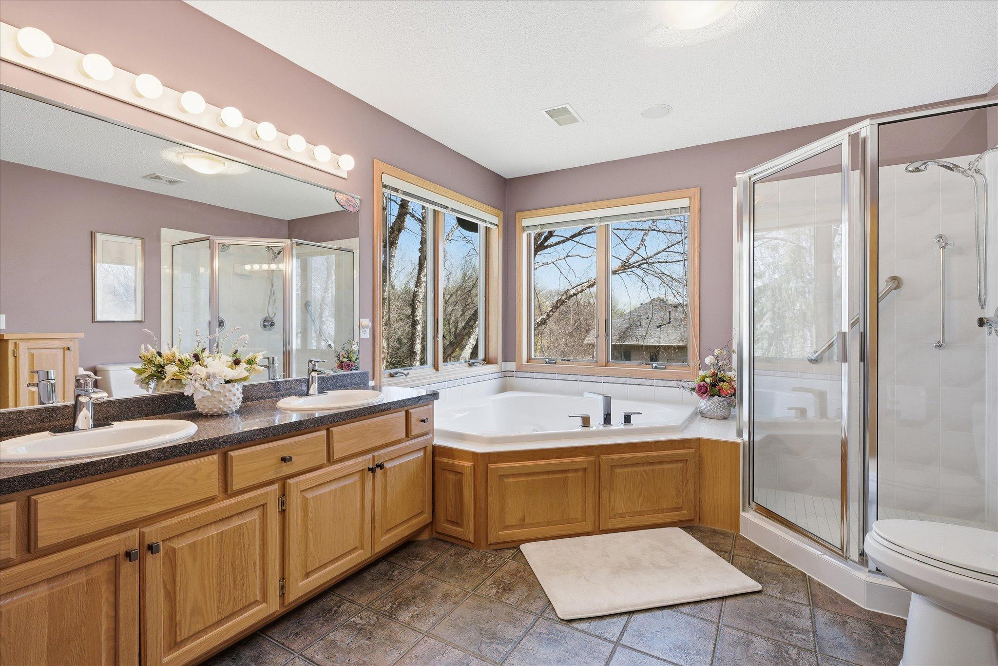 Primary Bathrm On-Suite features: dual sink vanity, corner whirlpool tub w/new faucet, tile floors (partially heated) and full shower w/glass door