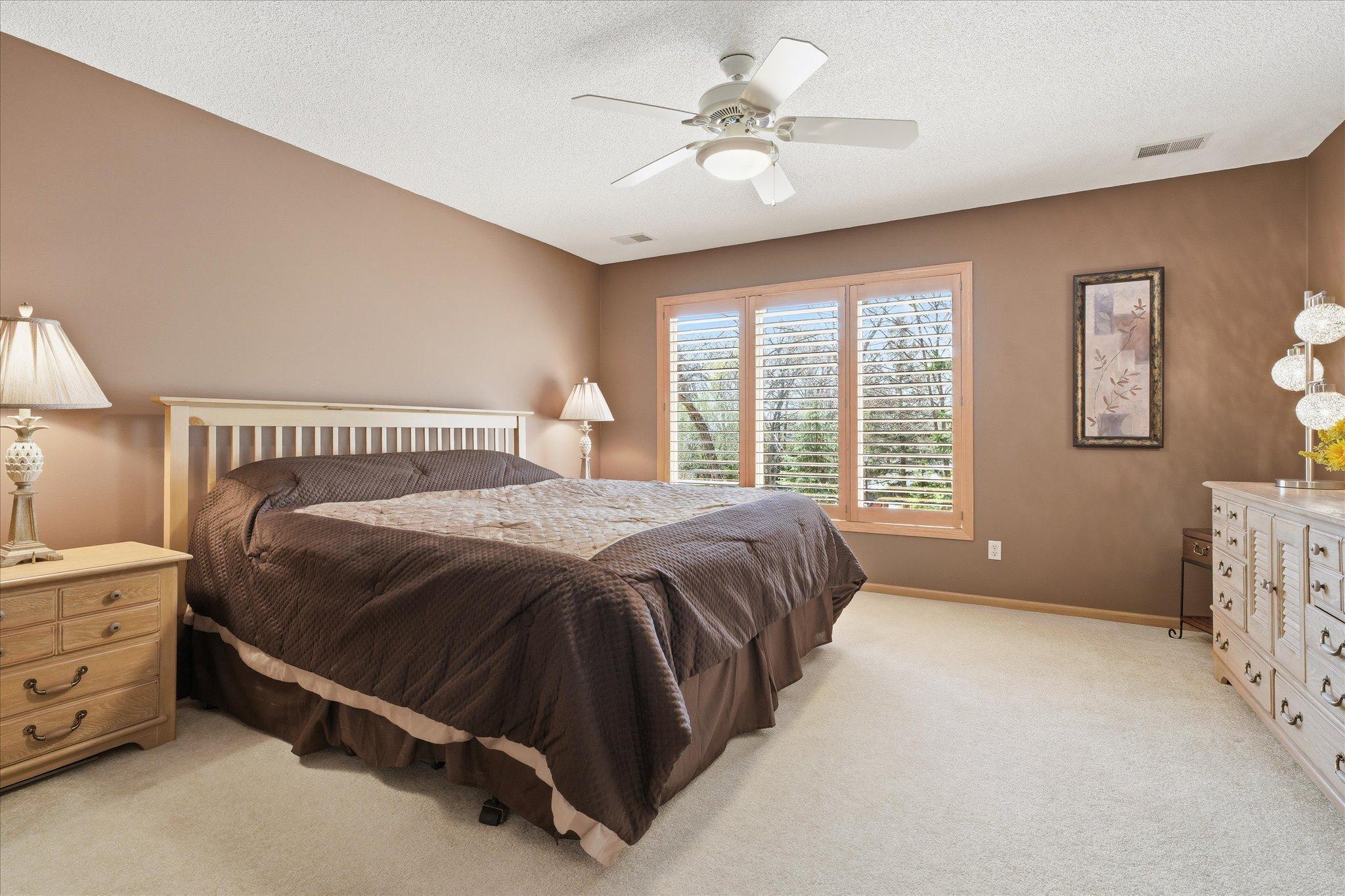 Spacious Primary Bedroom Suite features: huge walk-in closet, neutral carpet, tasteful paint, quality wood louvers blinds and ceiling fan/light
