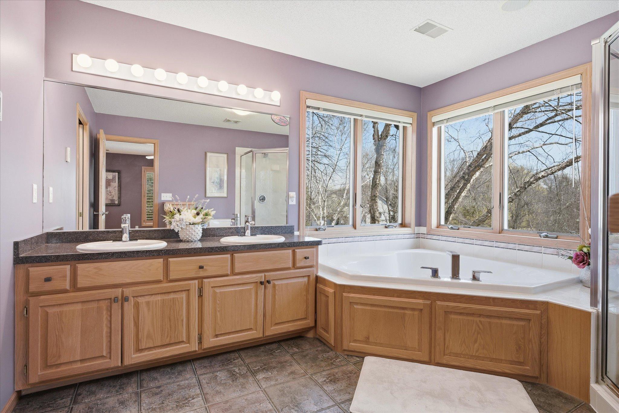 Primary Bathrm On-Suite features: dual sink vanity, corner whirlpool tub w/new faucet, tile floors (partially heated) and full shower w/glass door