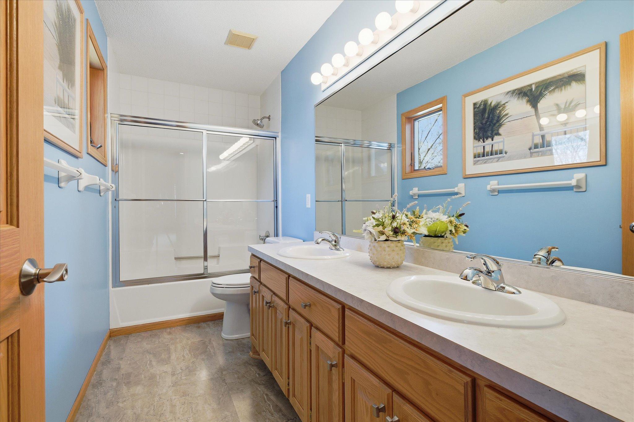 Upper level Full Bathroom features: double sink vanity, tub w/sliding glass doors and updated floor