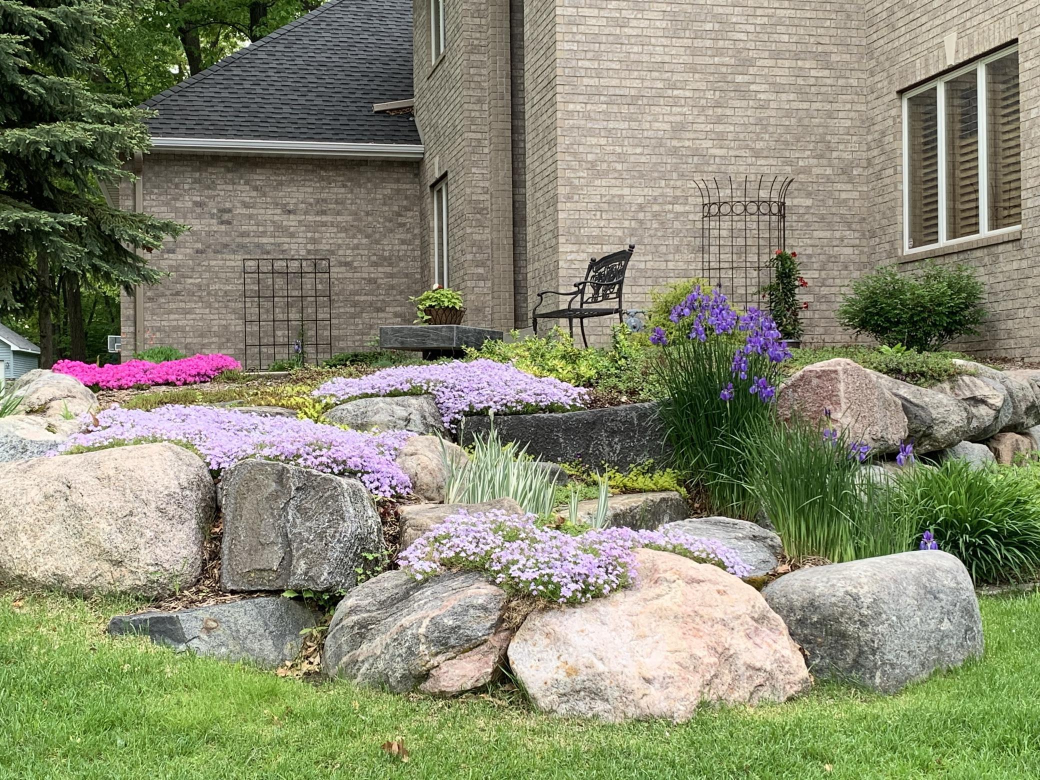 Beautiful landscaping includes: three landscaped berms, custom boulder retaining walls w/boulder steps, stone edging, numerous colorful perennial flowers/plants and mature trees throughout the entire front + back yards