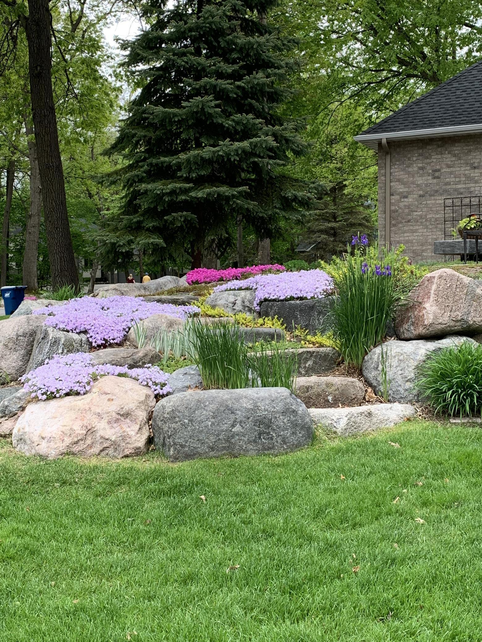 Beautiful landscaping includes: three landscaped berms, custom boulder retaining walls w/boulder steps, stone edging, numerous colorful perennial flowers/plants and mature trees throughout the entire front + back yards