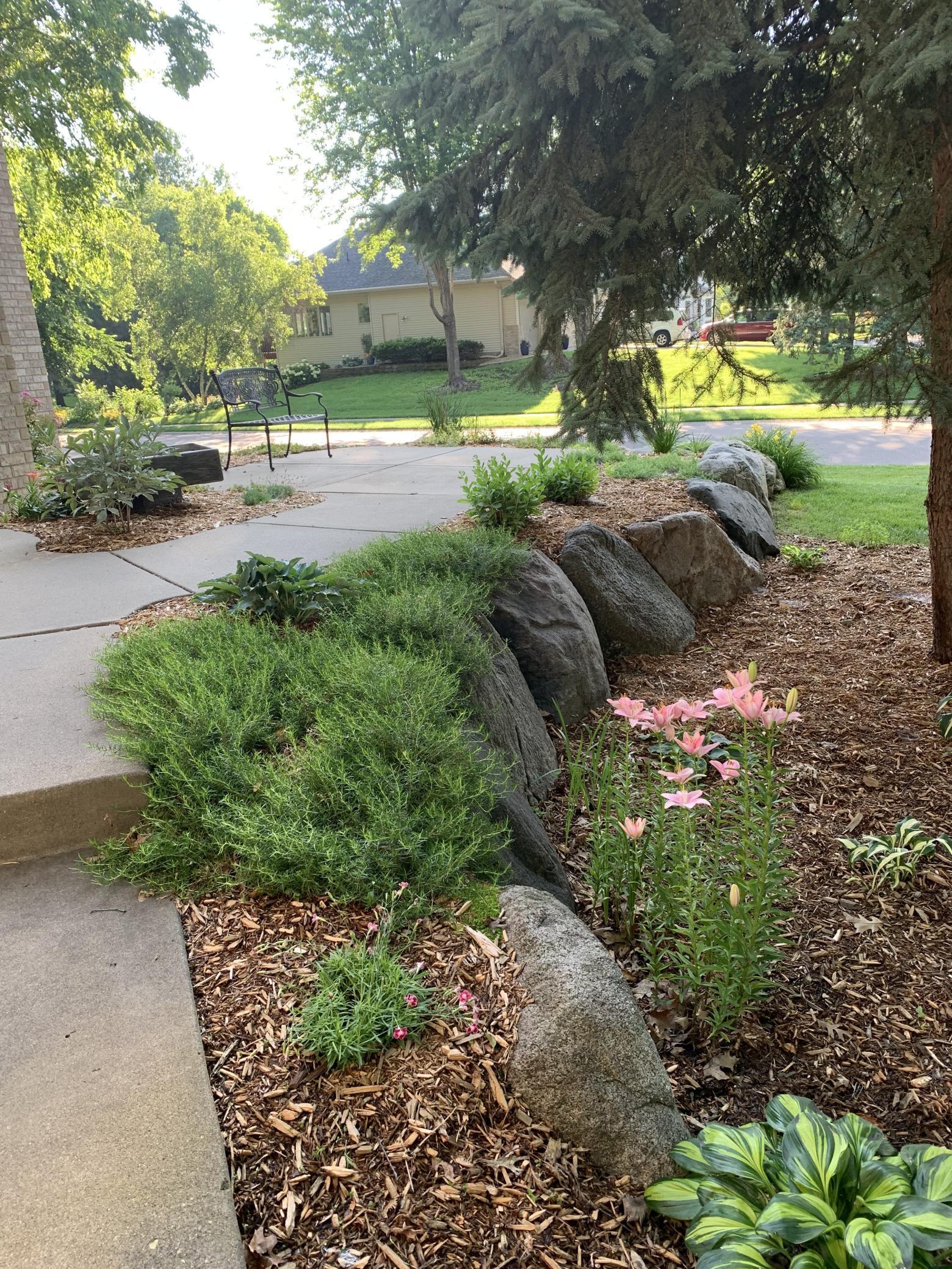 Private front sidewalk with professionally landscaped boulders, plantings and mature trees
