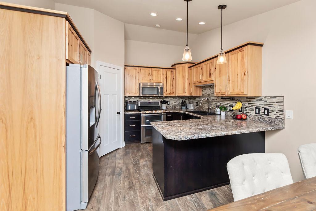 Two-tone wood cabinets, pendant lighting over the breakfast bar, stainless appliances