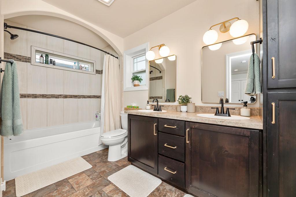 Primary Bathroom with double sinks, arched opening to tub/shower, tiled shower surround