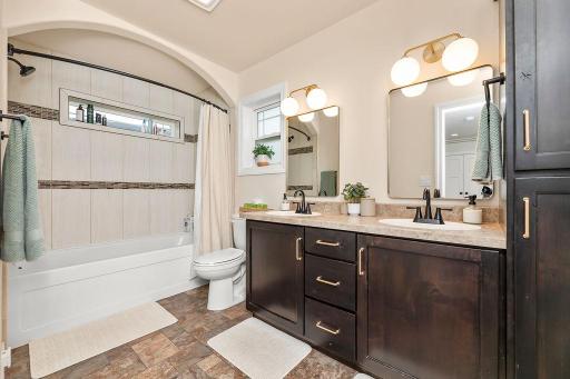 Primary Bathroom with double sinks, arched opening to tub/shower, tiled shower surround
