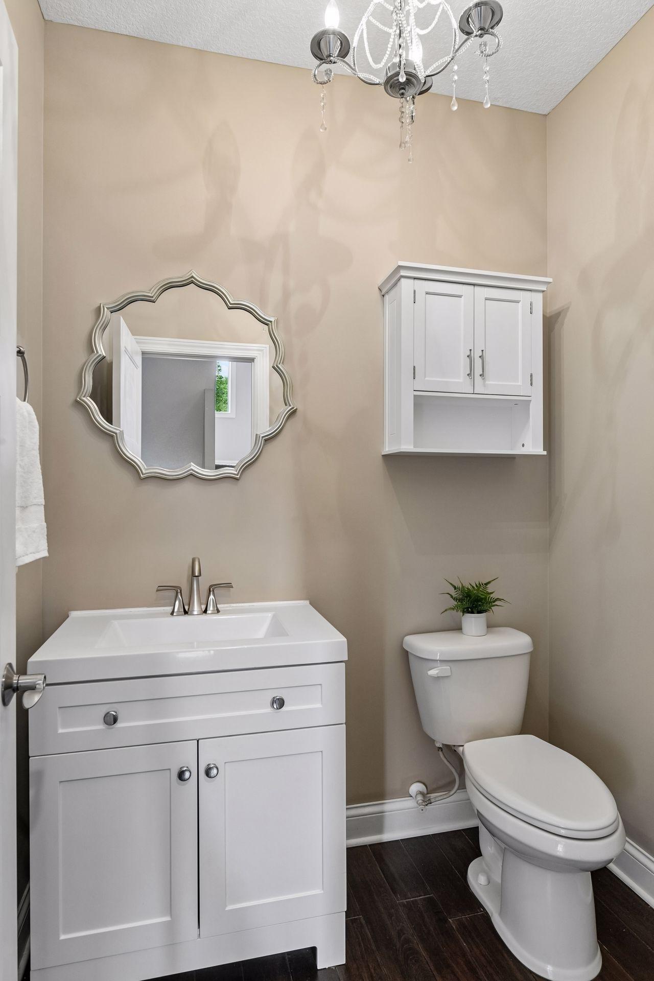 Half bath with pedestal vanity, framed mirror, and wall-mounted storage cabinet