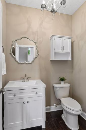 Half bath with pedestal vanity, framed mirror, and wall-mounted storage cabinet