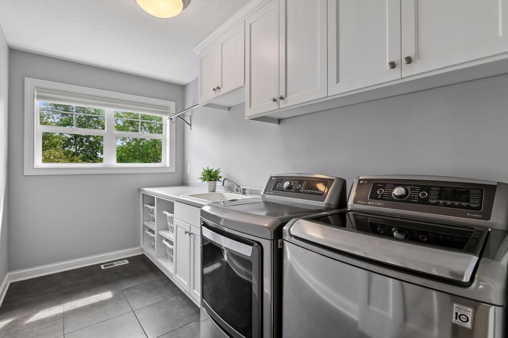 Upstairs laundry room with upper cabinetry, base cabinetry, countertop folding surface, and service sink.
