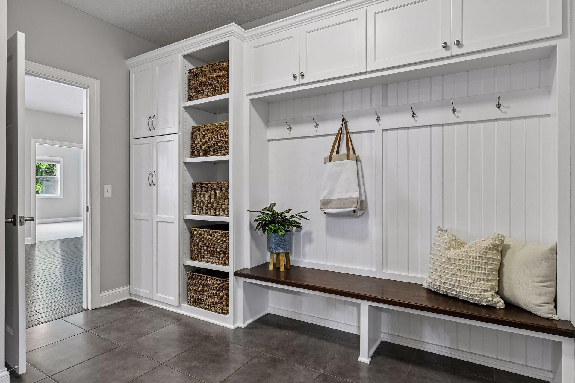 Mudroom with custom built-in bench, upper cabinetry, open cubby shelving