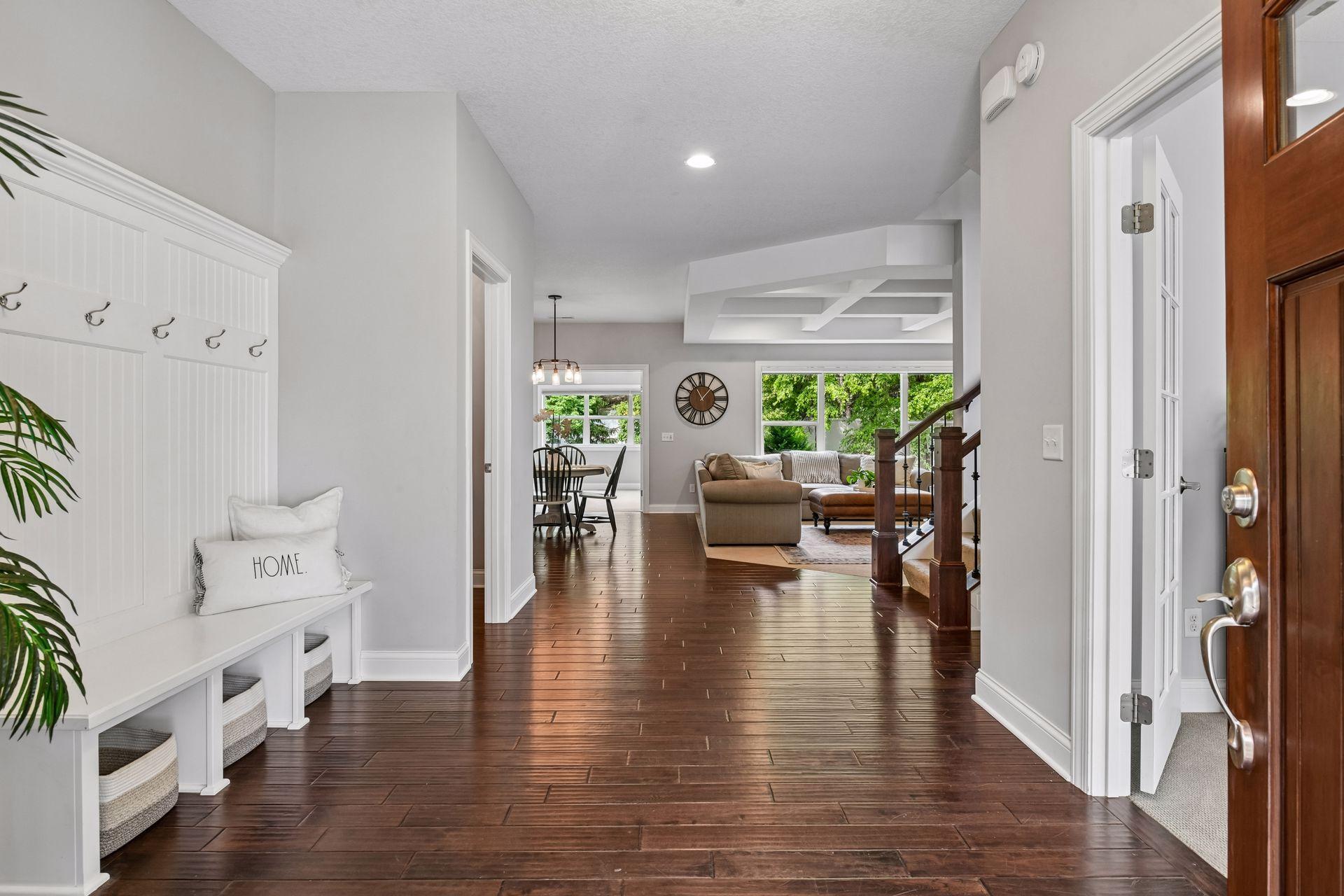 Front foyer opening to dining and living areas with hardwood flooring and vaulted coffered ceilings