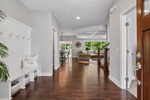 Front foyer opening to dining and living areas with hardwood flooring and vaulted coffered ceilings