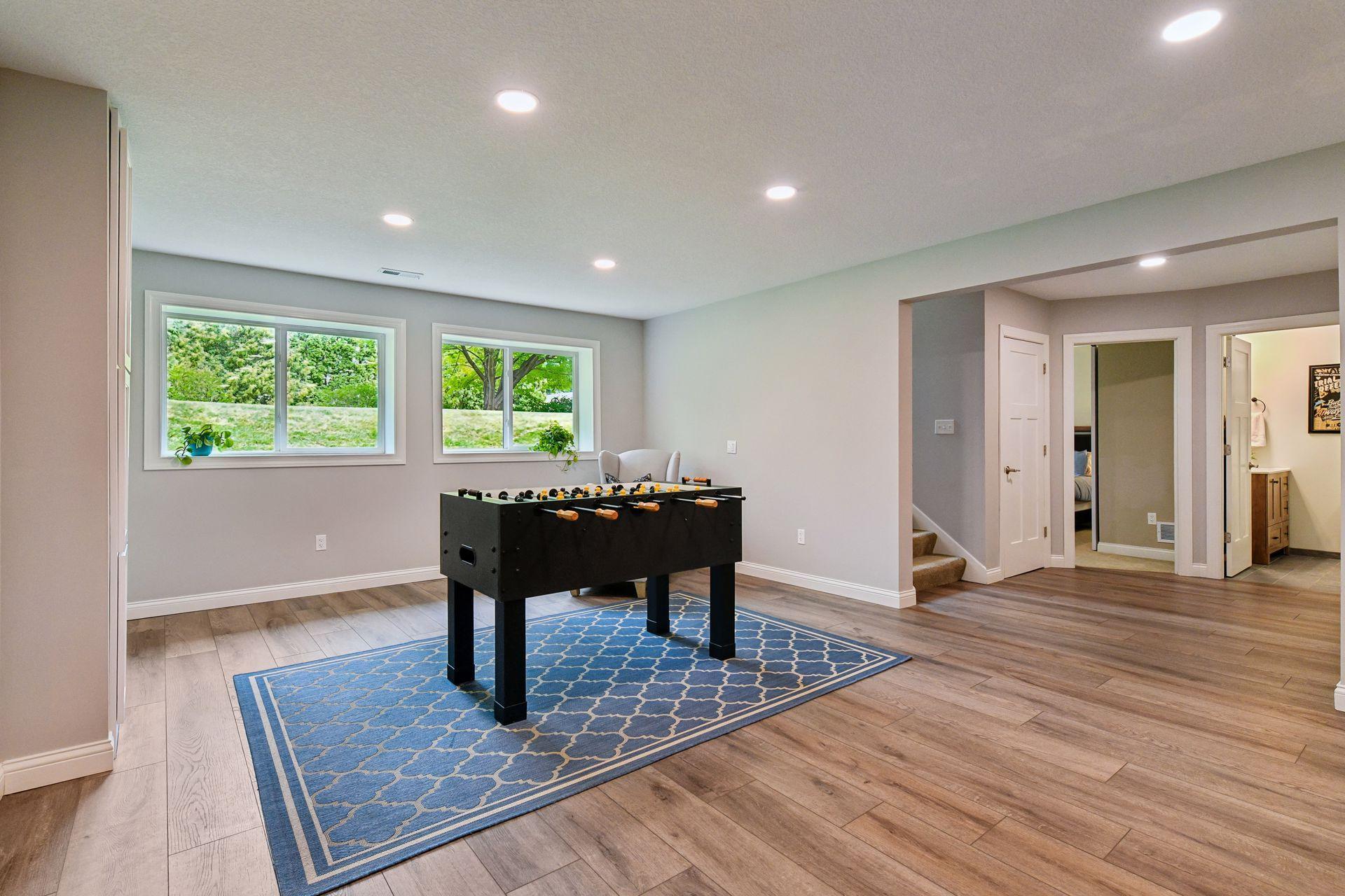 Lower level recreation area with window bank, recessed lighting, and hall access