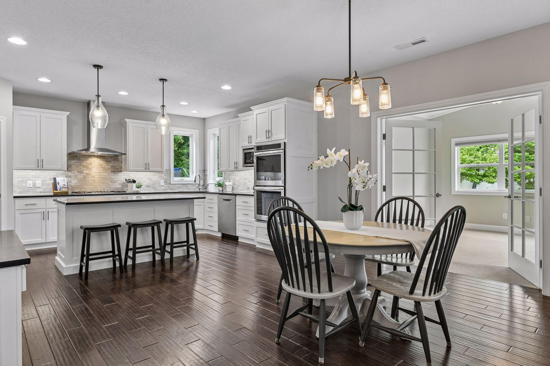 Informal dining area adjacent to kitchen with pendant and chandelier lighting and hardwood flooring