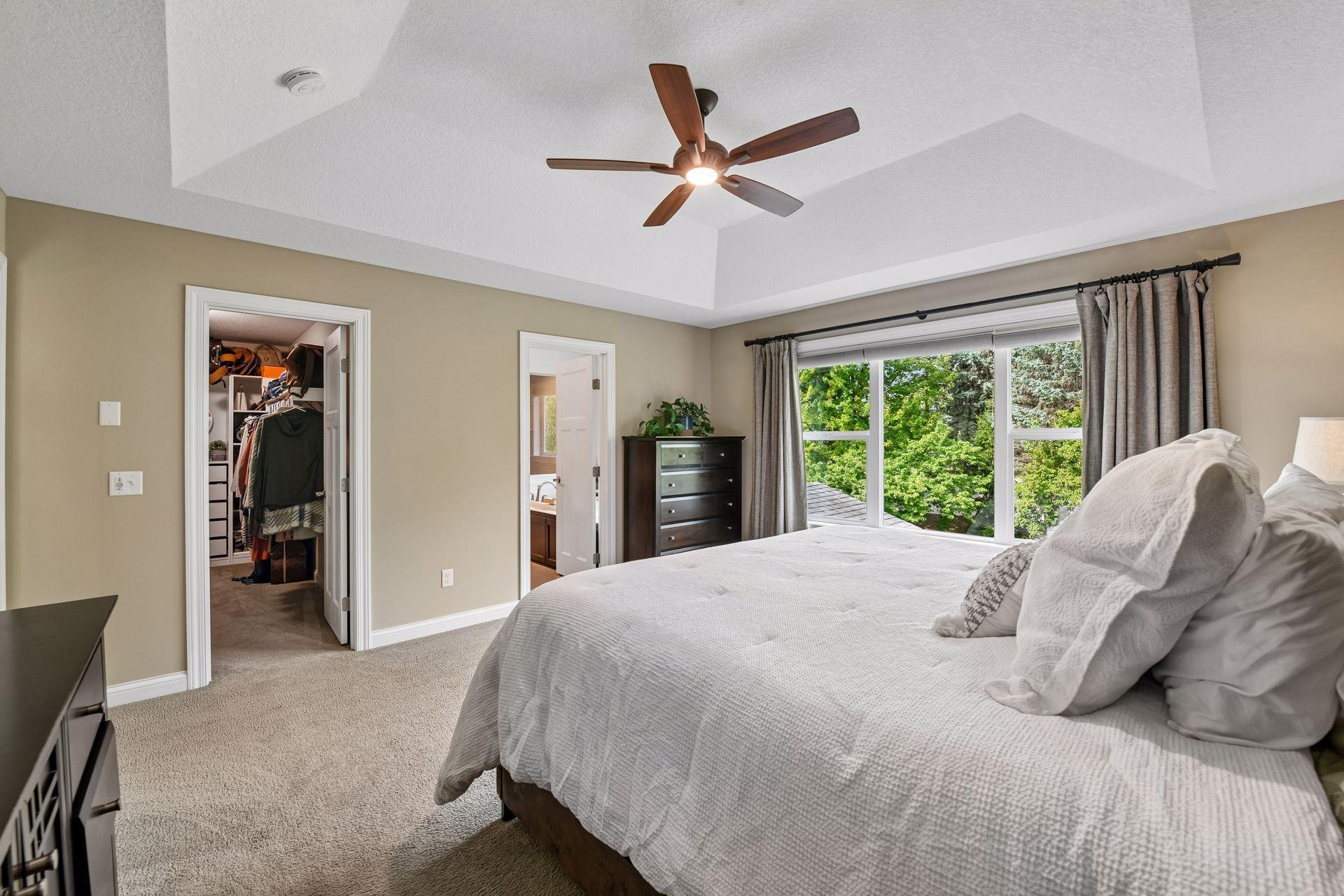 Primary bedroom with tray ceiling, walk-in closet access, and private bath entry