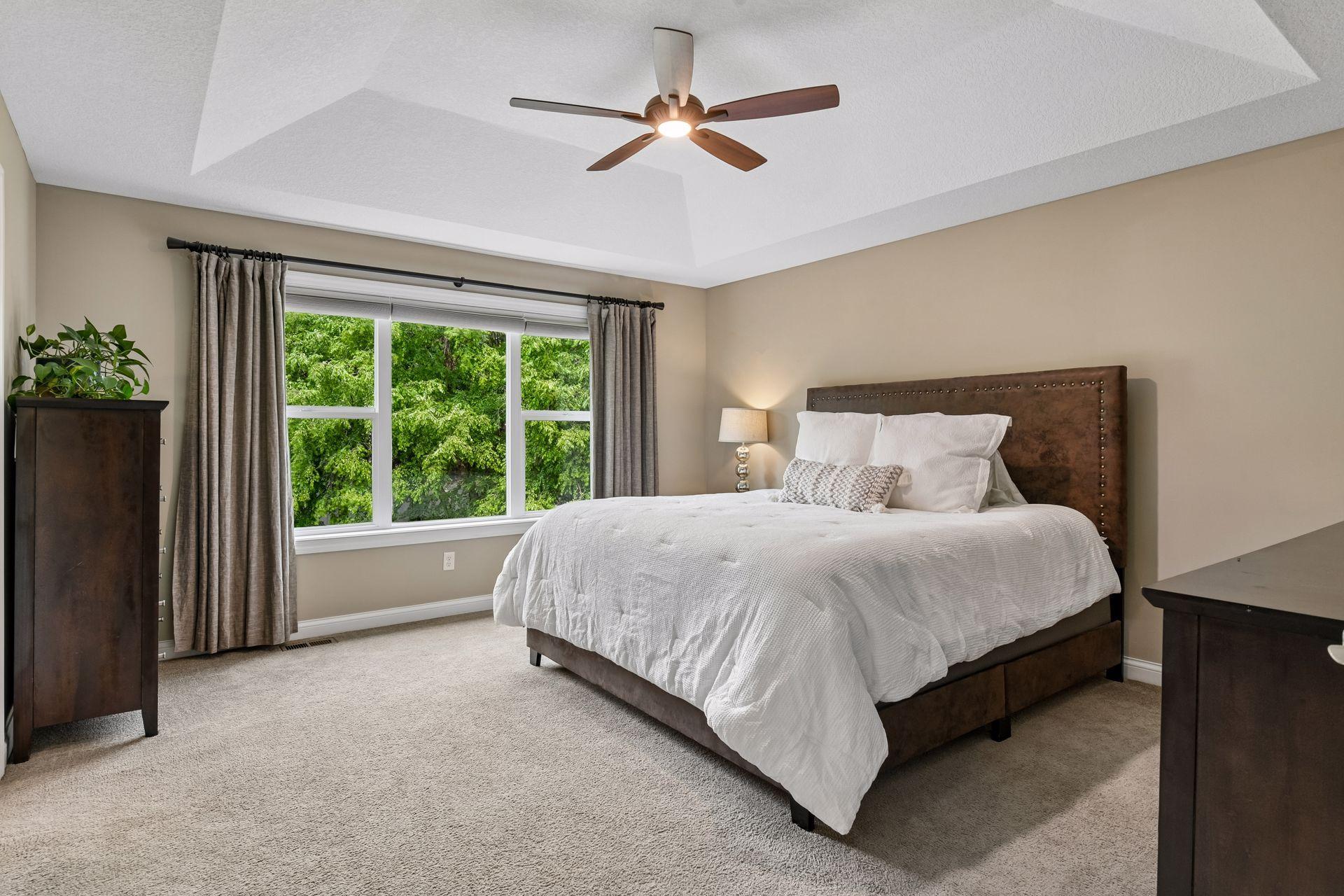 Primary bedroom with tray ceilings and large window with views out the back.