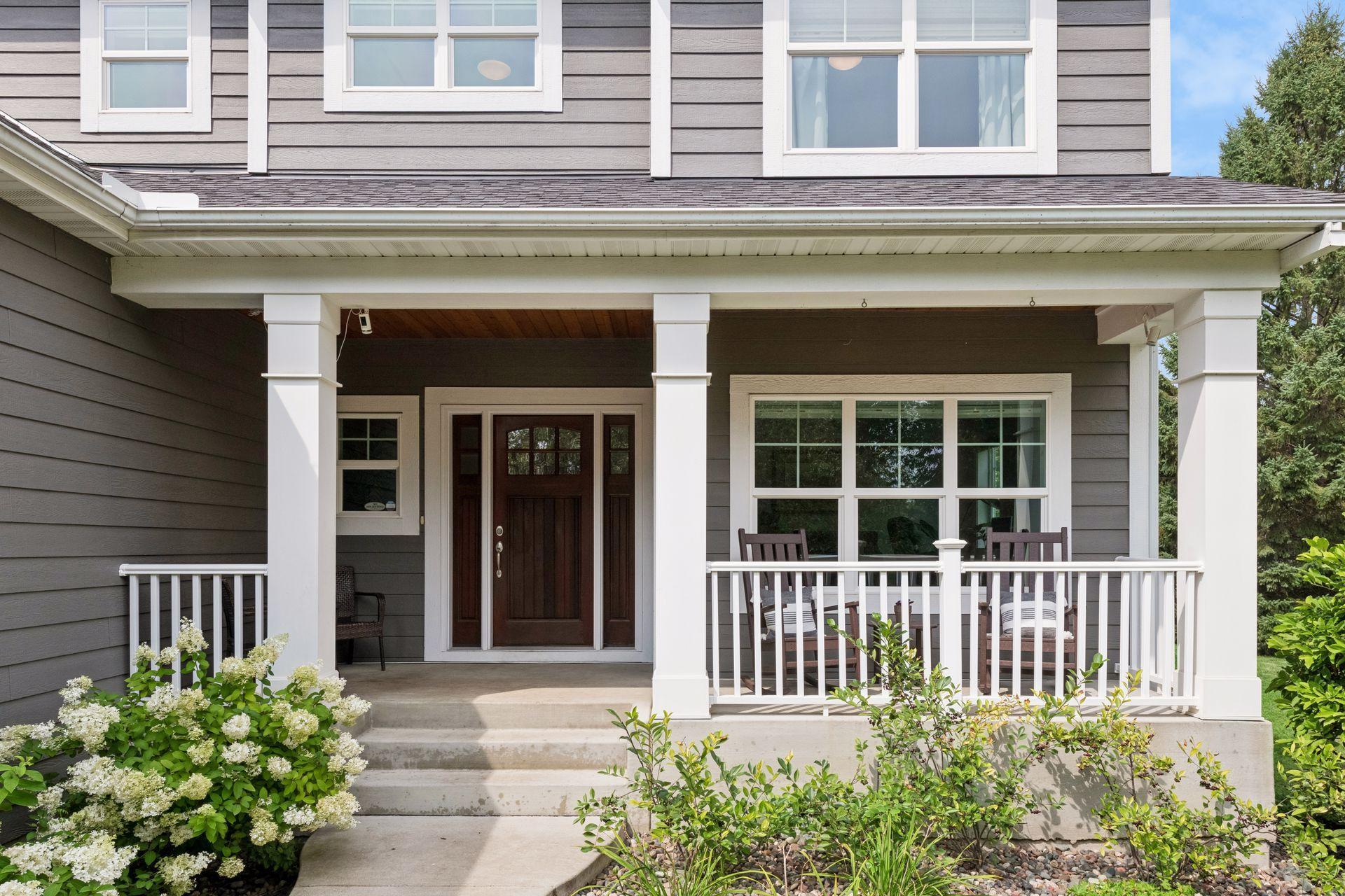 Covered concrete front porch with tapered columns and painted railing