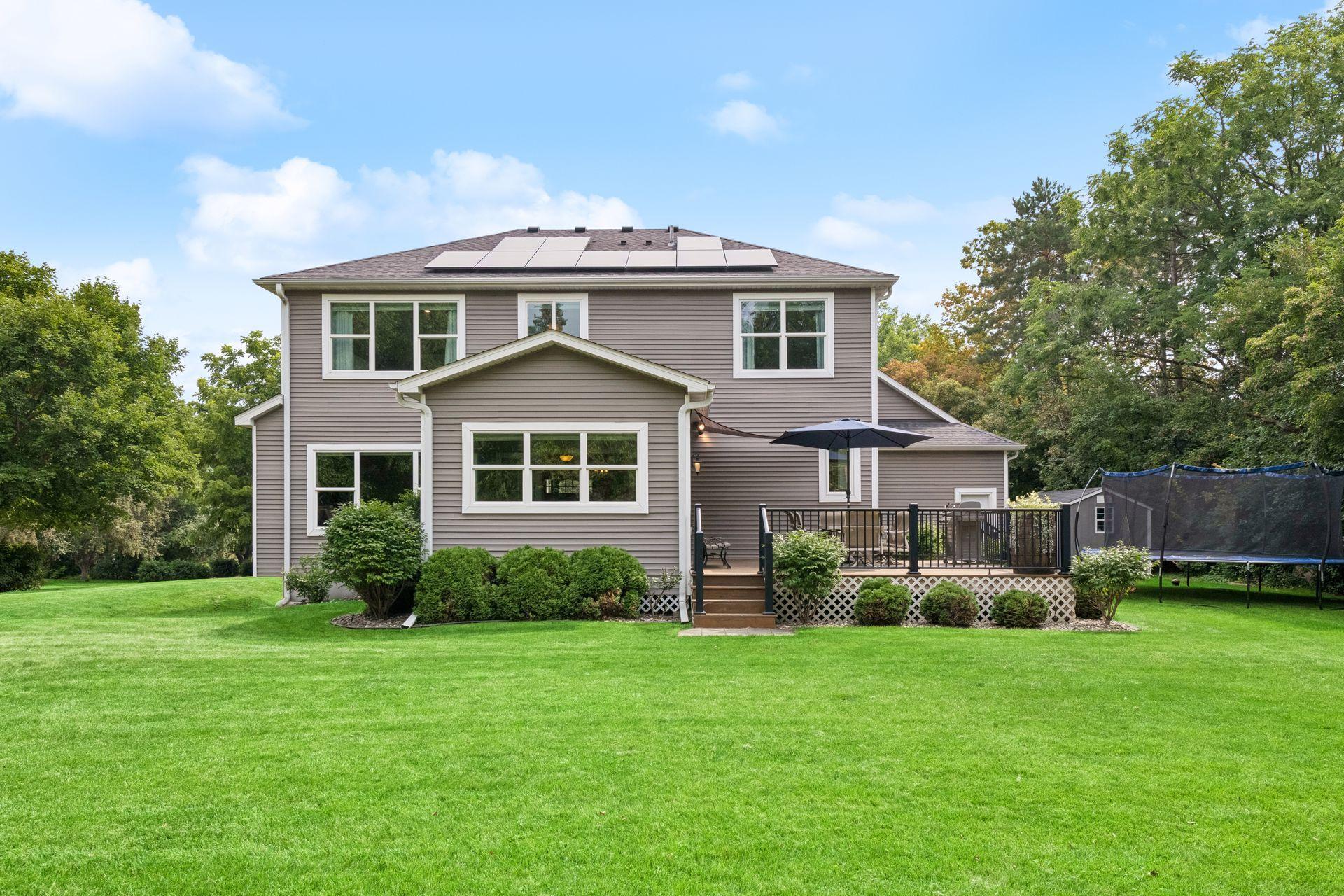 Back of home with raised deck, walkout access, and mature landscaping