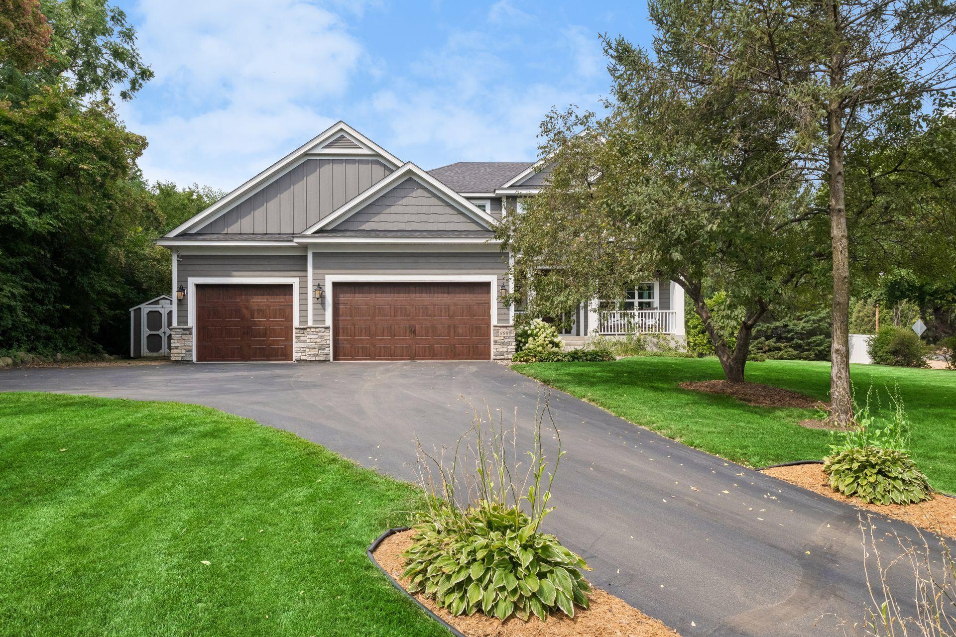 Front elevation with three attached garage stalls, shake and lap siding, and landscaped island bed