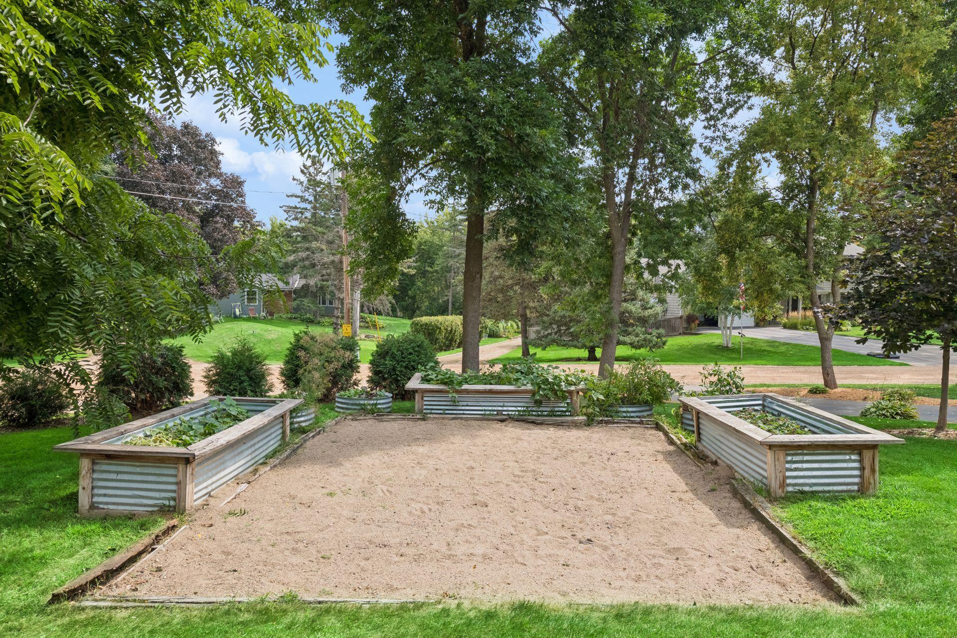 Raised garden beds with gravel surround and mature tree canopy