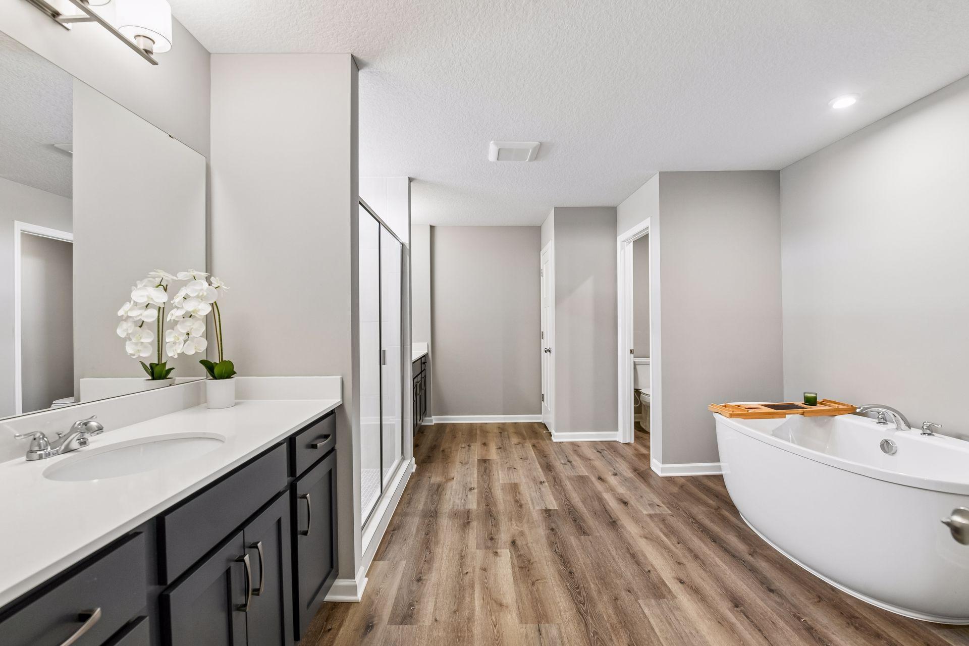 Primary bathroom includes dual vanities, tiled walk in shower, soaking tub and large walk in closet