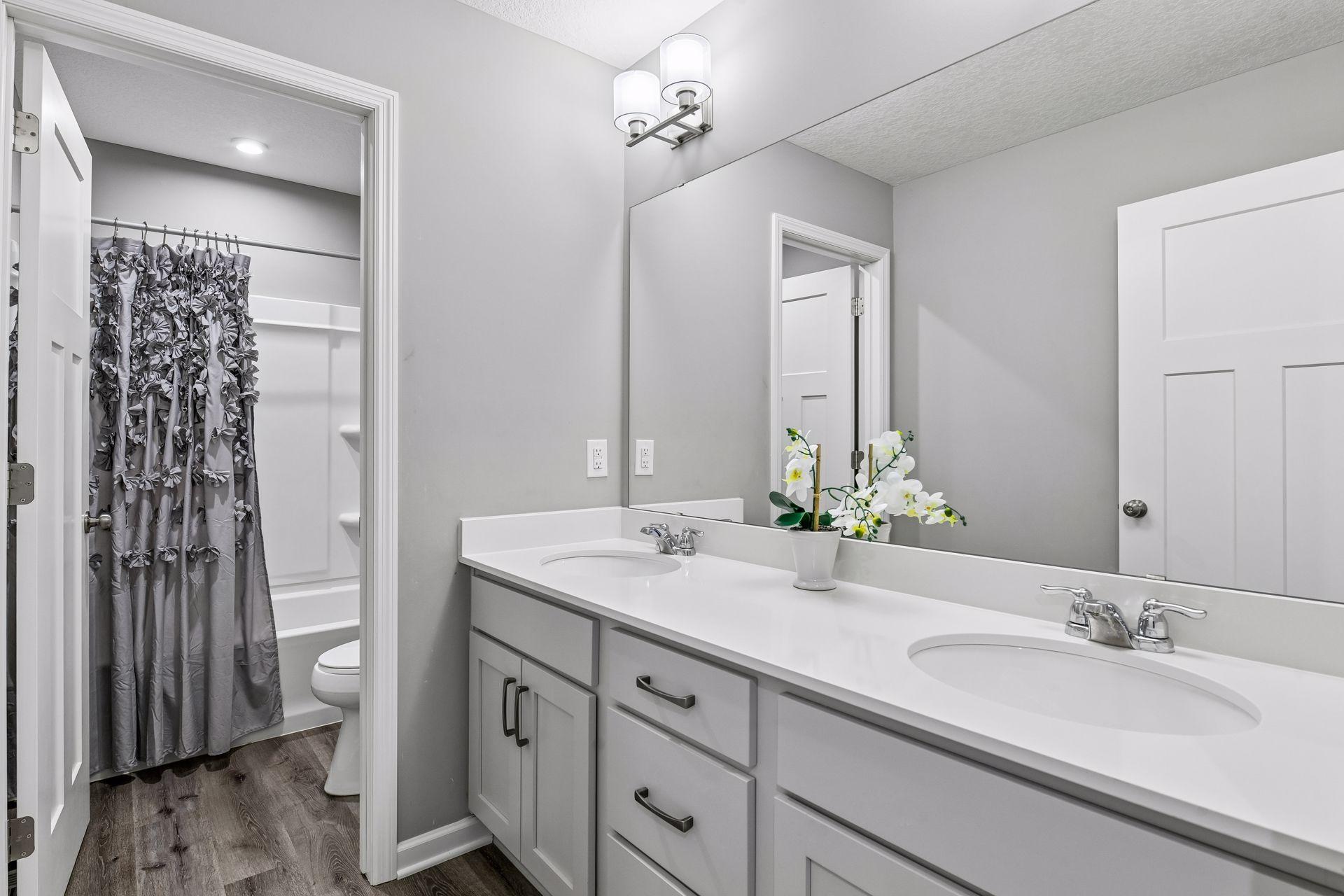 Third bathroom on the upper level with dual sinks and separate space for shower and toilet
