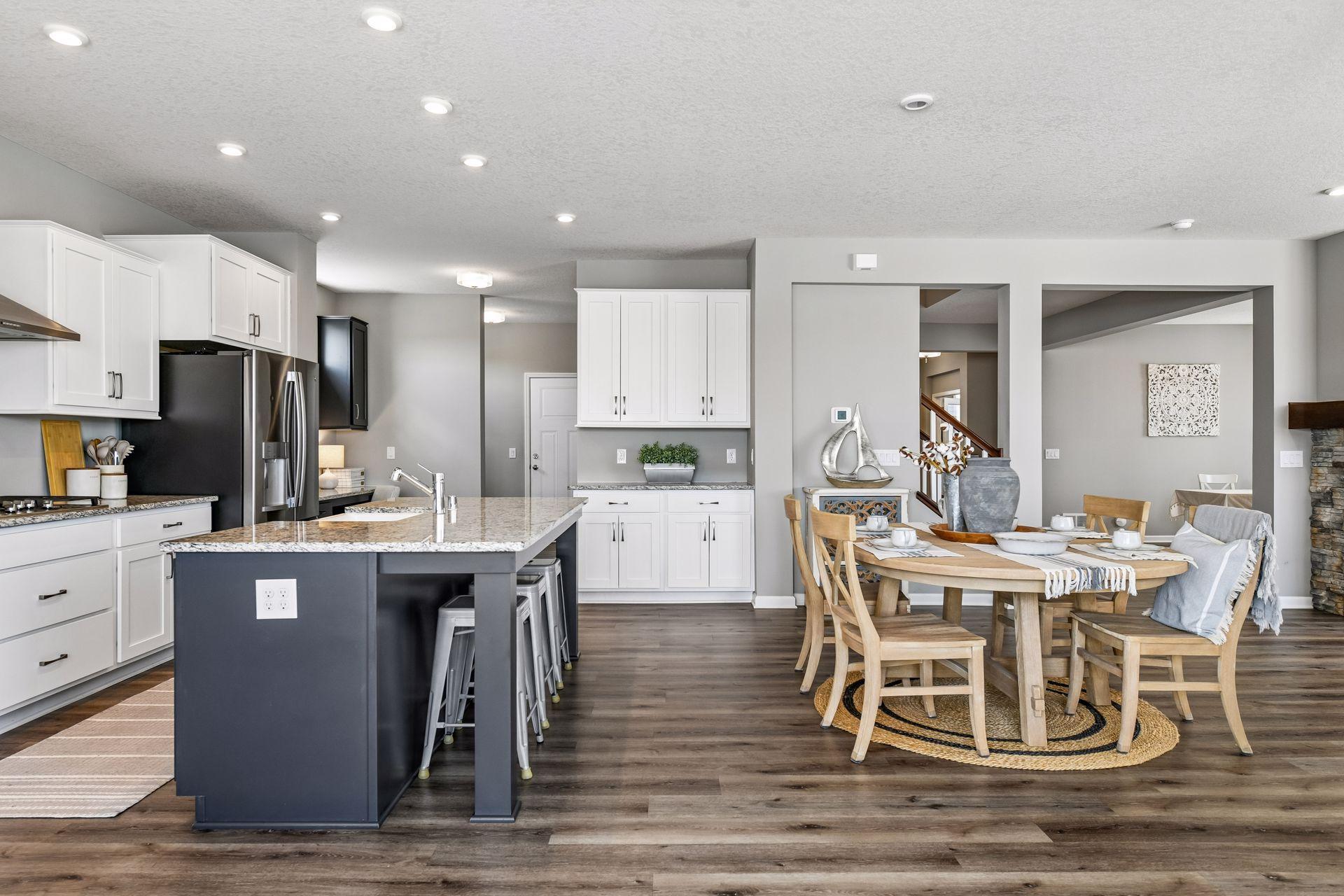 Oversized center island with bar seating anchors the open concept main floor, flowing into casual dining, the family room with fireplace, and a built-in tech nook by the entry.