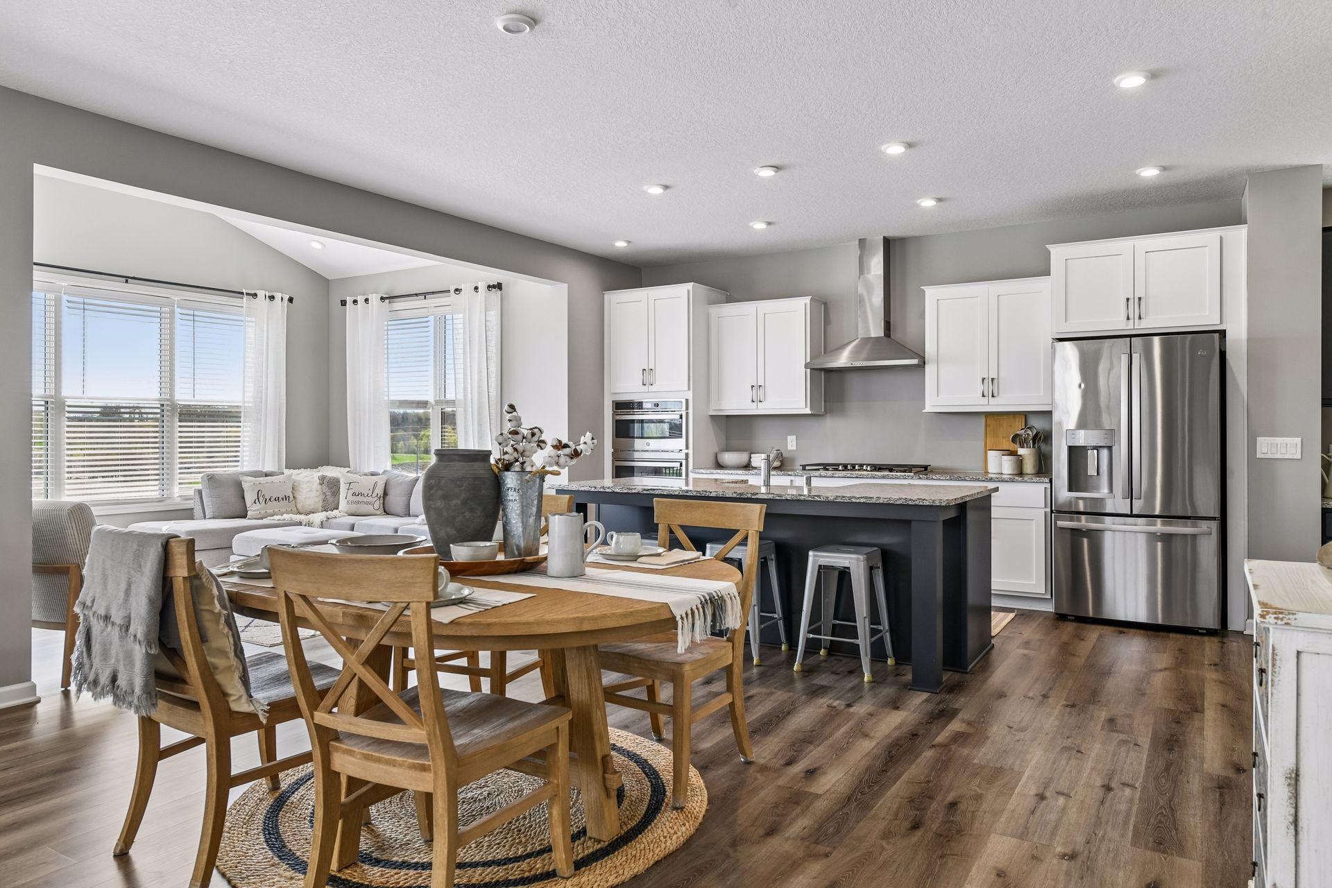 Chef's kitchen with granite countertops, stainless steel appliances, gas range, and oversized center island, open to casual dining and a vaulted sun room.