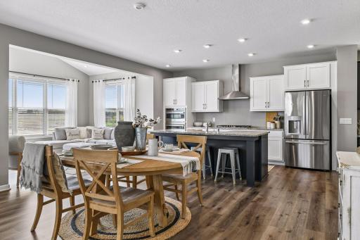 Chef's kitchen with granite countertops, stainless steel appliances, gas range, and oversized center island, open to casual dining and a vaulted sun room.