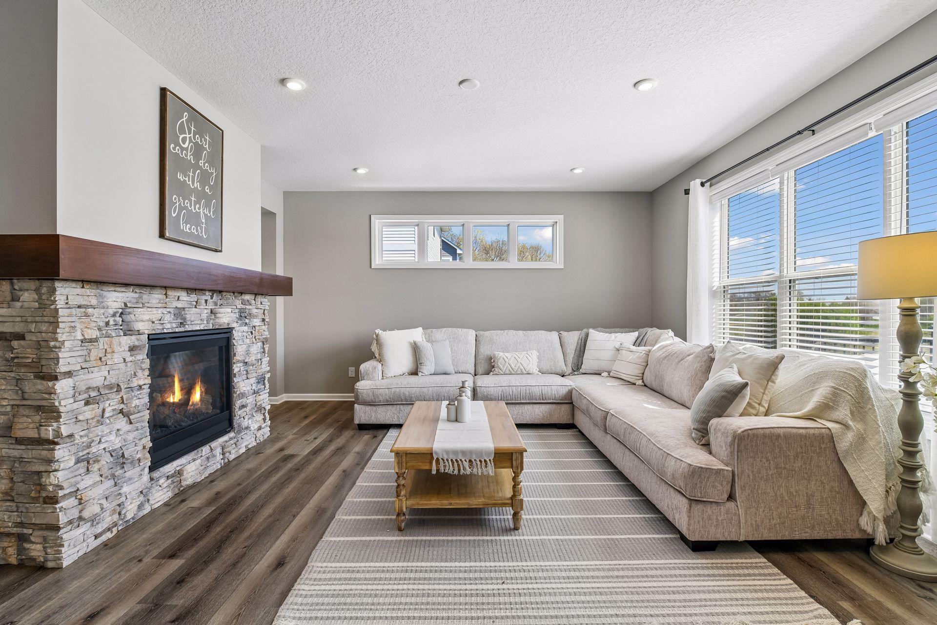 Living room space features stacked stone gas fireplace and transom windows that flood this space with eastern facing daylight