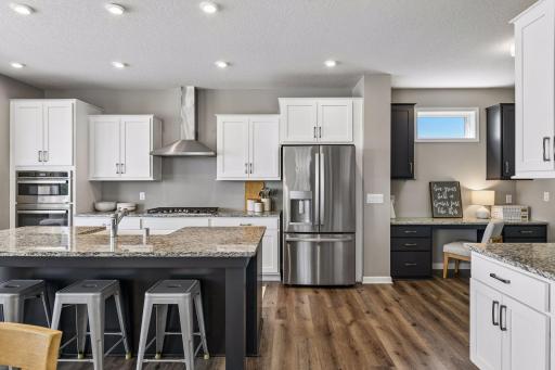 Built-in tech nook with contrast cabinetry and granite countertops, tucked just off the chef's kitchen with wall ovens, gas range, and French door refrigerator.