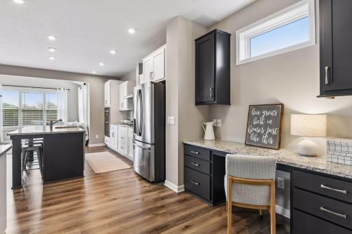 Built-in tech nook with contrast cabinetry, granite surface, and dedicated workspace just off the kitchen.