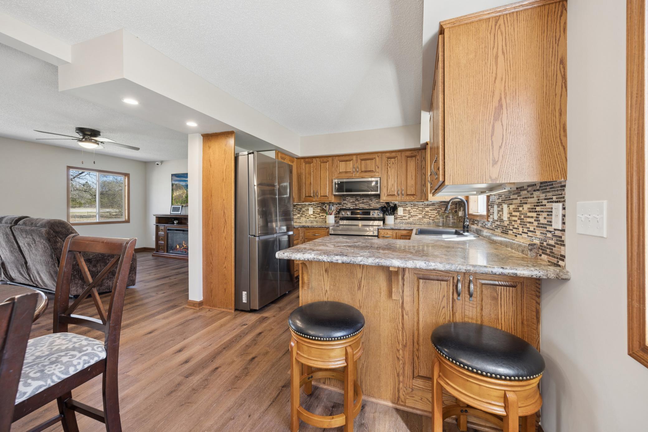 Kitchen area offers quality solid oak cabinetry, a peninsula island with added counter seating, backsplash, and SS appliances!